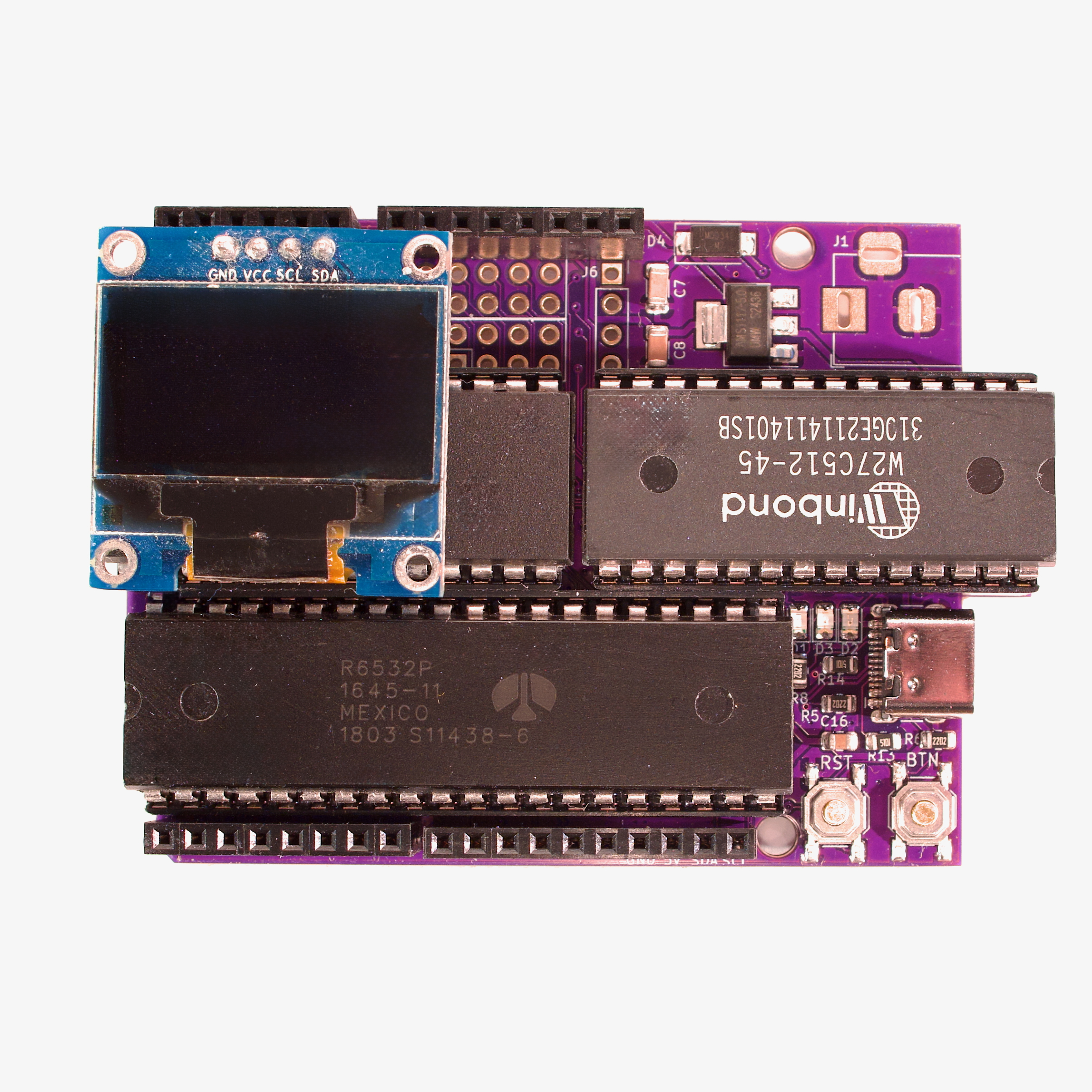 Populated purple 65uino board with blue OLED module mounted above the 6507 and 6532 chips